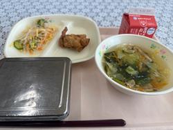 ピンクのトレーに給食が左から時計回りに春雨サラダ、鶏肉のから揚げ、牛乳、チンゲン菜のスープ、ごはんが並んでいる写真