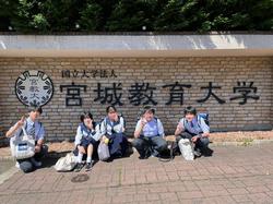 宮城教育大学と書かれた壁の前で男女5人の生徒が並んで座って写した記念写真