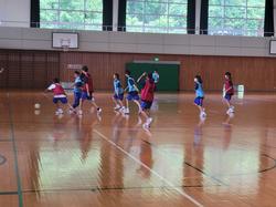 体育館でビブスをつけた複数の生徒たちが、サッカーの授業を行っている様子の写真