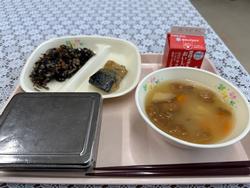 ピンクのトレーに給食が左から時計回りにひじきの煮物、サバの味噌煮、牛乳、あぶら麩の味噌汁、ごはんが並んでいる写真