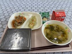 ピンクのトレーに給食が左から時計回りに豚肉とごぼうの味噌炒め、笹かまの磯部揚げ、ふりかけ、牛乳、ワカメの味噌汁、ごはんが並んでいる写真