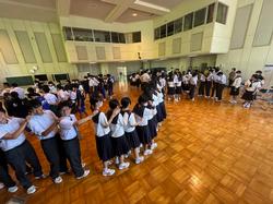 体育館で大勢の生徒が前の生徒の肩に両手を乗せて長い列を作り、じゃんけん列車を楽しんでいる写真