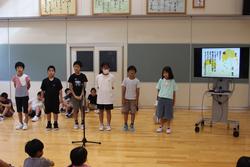 映像が映されたモニターの横に6名の生徒が横一列に並び発表をしている様子を写した写真