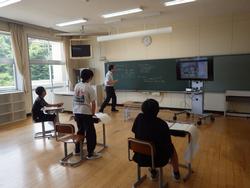 授業を受けている複数の生徒たちと、黒板の前で先生が解説をしている学校の教室の様子を撮影した写真