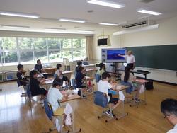 席についている生徒たちがいる教室の前方で、野口英世記念館の講師の方がモニターを使いながら生徒たちに話をしている出前授業の写真