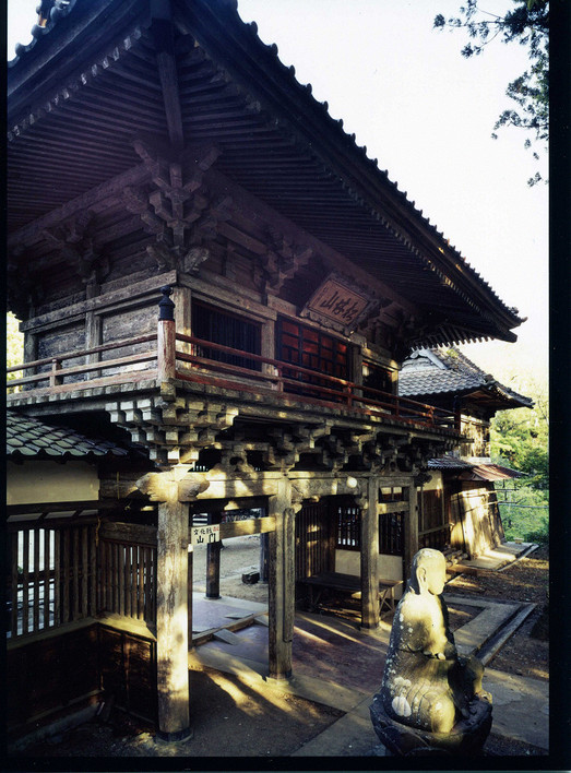 木造二層建ての山門と前方の石像を写した大雄寺の山門・鐘楼の写真