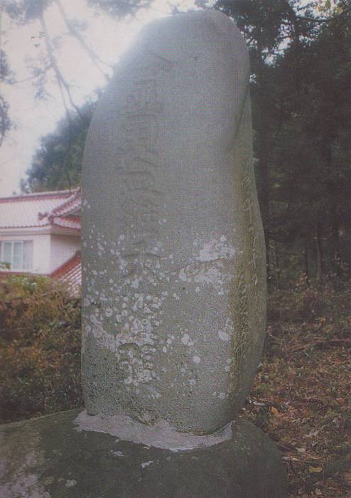 縦長の石碑で、表面には縦書きの文字が刻まれているが風化や苔で判読しにくくなっている金毘羅大権現碑の写真