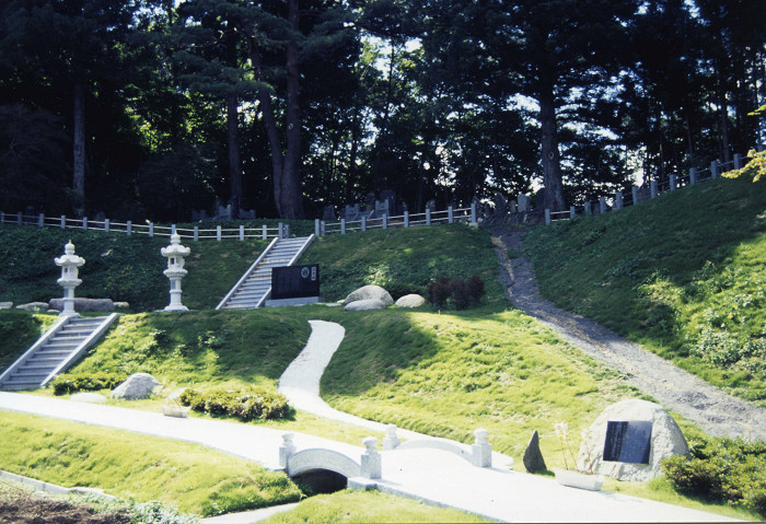 石灯籠や岩、小道が配置され、苔や木々に囲まれた山内甚之丞・甚兵衛父子の墓所の写真