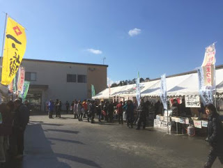 左右に並んでいるのぼりが立ったテントそれぞれにたくさんの来場者が集まっている写真