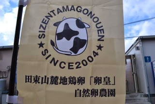 「SIZENTAMAGONOUEN SINCE 2004」と牛のロゴが描かれ、田束山産地鶏卵「卵皇」と書かれたのぼり旗の写真