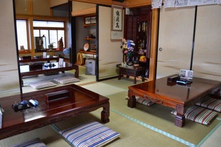 和風の畳敷きの店内に複数の座卓と座布団が並べられ、仏壇や掛け軸、飾り棚がある部屋を写した写真