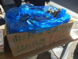 「南三陸産塩蔵ワカメ詰め放題500円」と書かれた段ボール箱に、青いビニール袋に入ったワカメが入っている写真