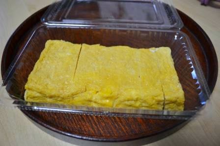 きれいに切り分けられた黄色い出汁巻き卵が透明なフタ付き容器に入っているテイクアウトの玉子焼きの写真