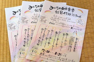 「みんなの町民憲章虹色イラストコンクール」と題した応募用紙が畳の上に3枚重ねて置かれている写真