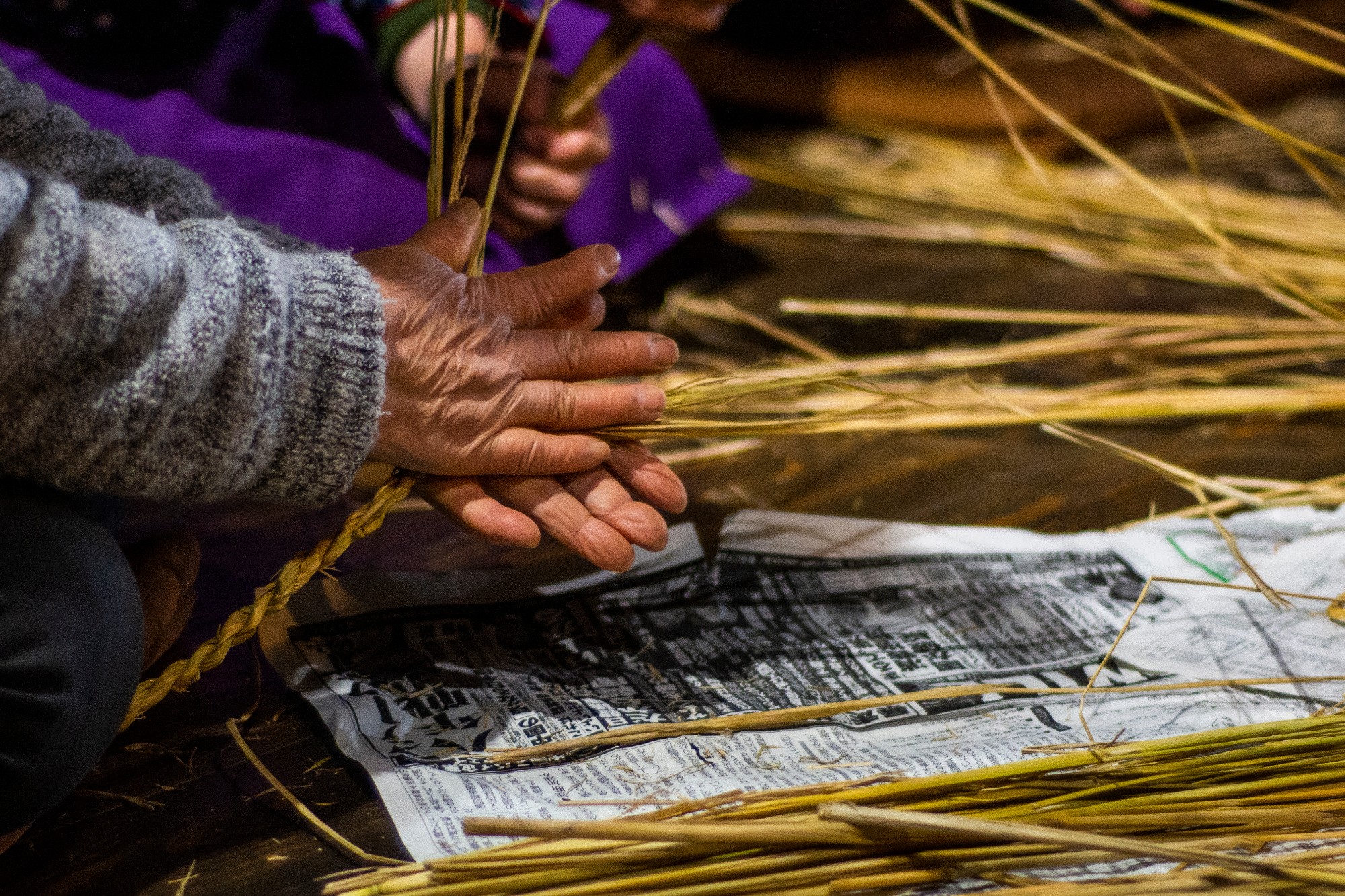 数人が集まって藁を編んでいる作業の様子が写っている写真