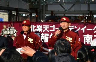 楽天イーグルスの優勝報告会で、ステージ上に立った牧田明久外野手と斎藤隆投手が、集まったファンの前で笑顔で挨拶している写真