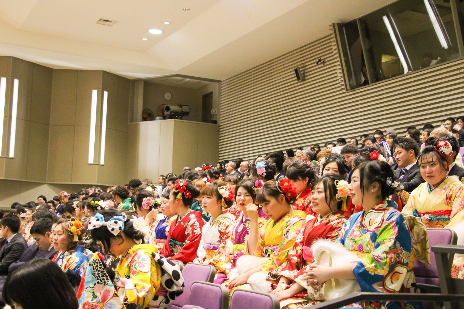広い体育館の中に、色とりどりの振袖や落ち着いた色のスーツを身につけた新成人たちが座っている会場内の写真