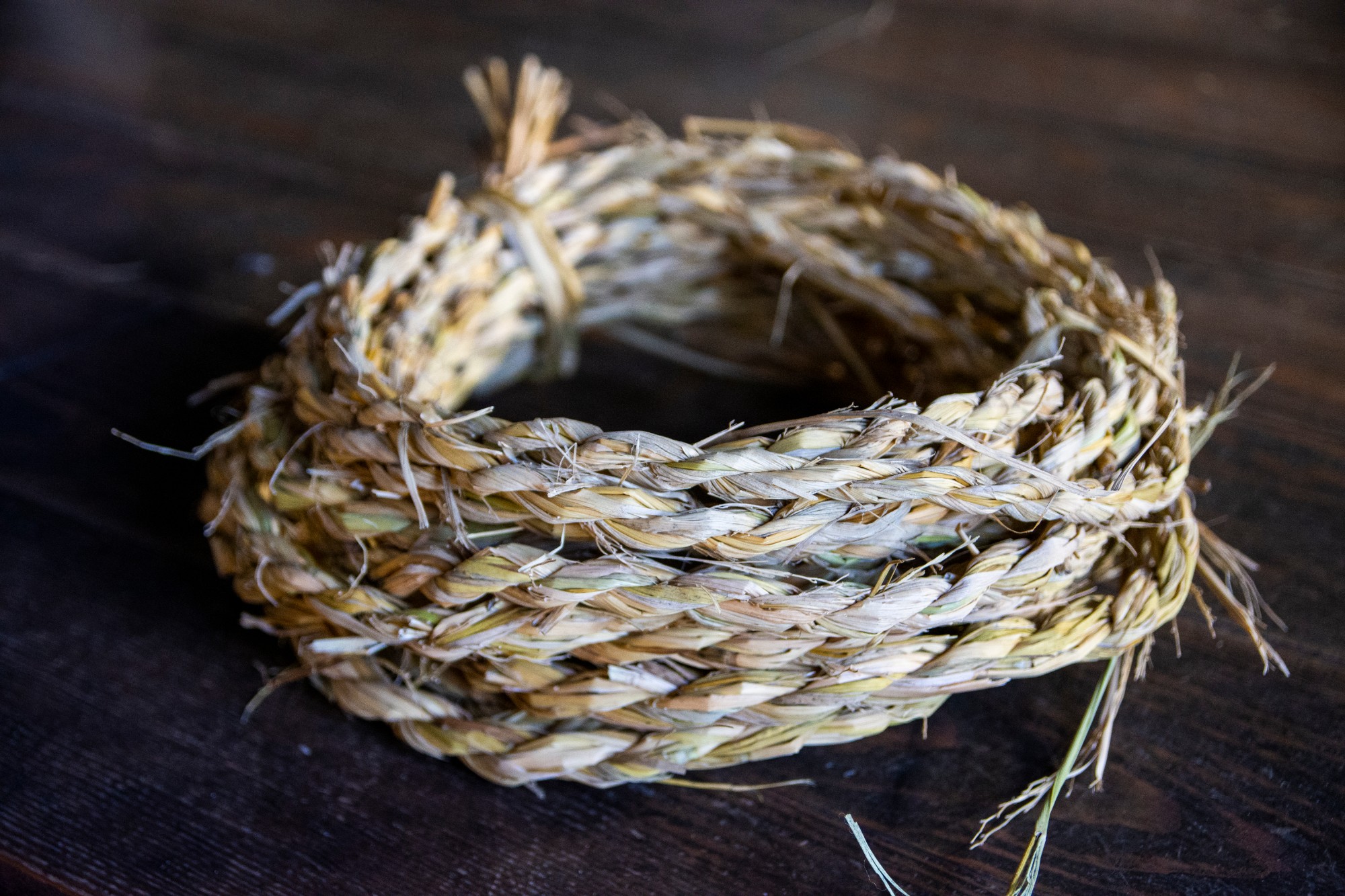 藁で編まれた縄が丸く巻かれて床の上に置かれている写真