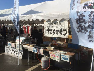 「たらすもづ」と大きく書かれた看板を掲げた白い屋根のテントの写真