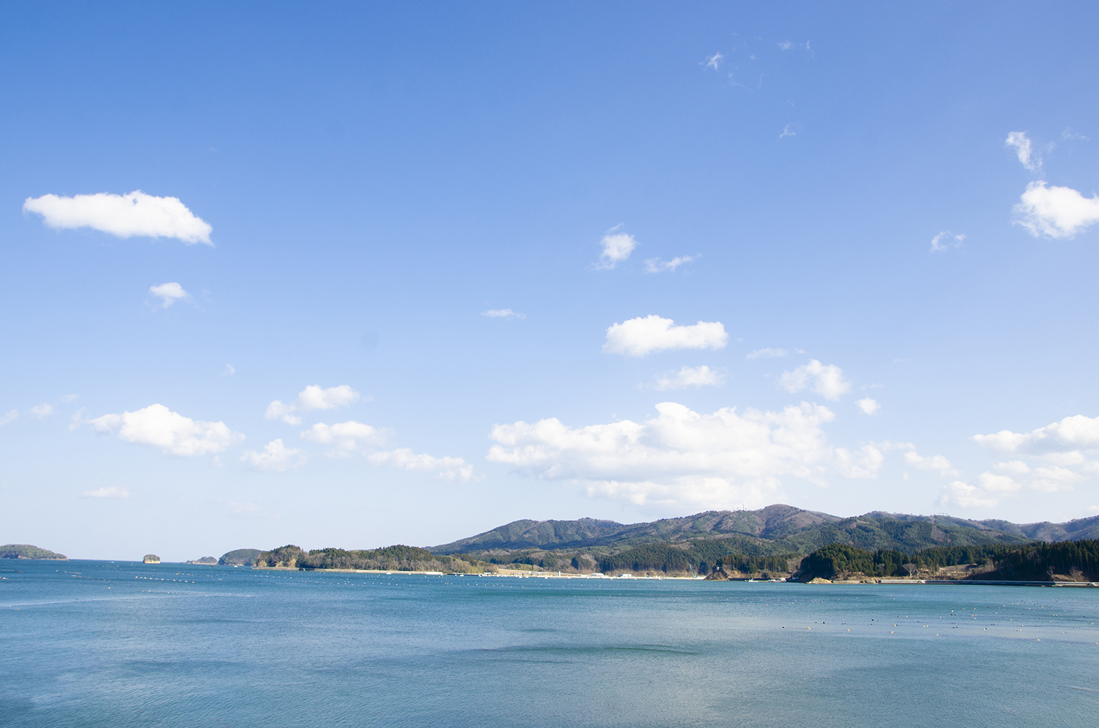 青い海と空、奥に山並みが広がる風景を写した写真