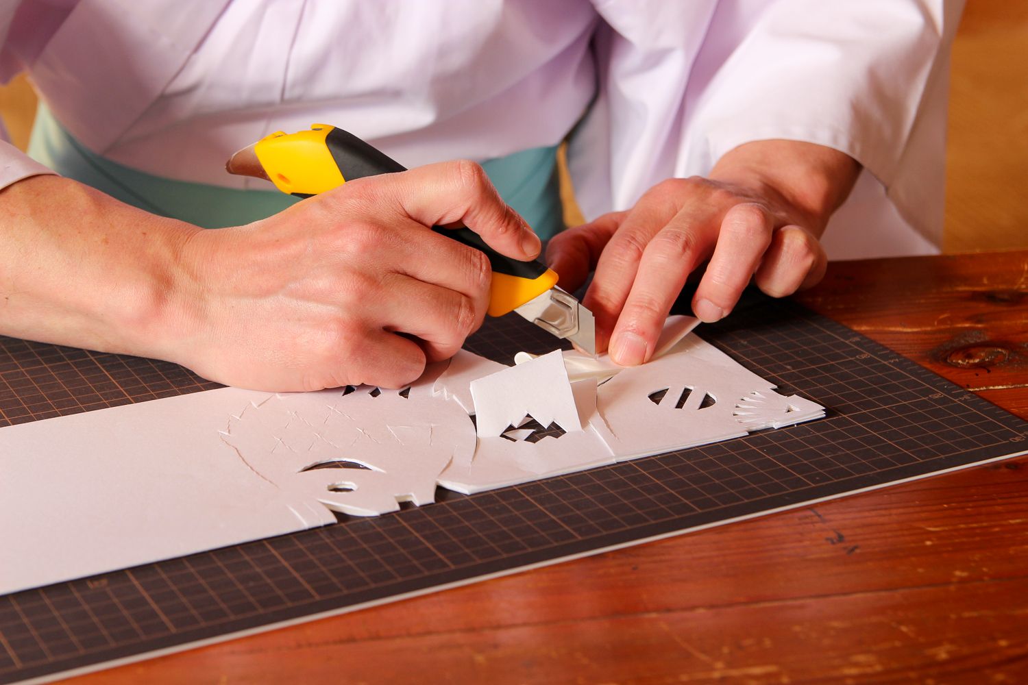 片手で定規をしっかり押さえ、もう一方の手に持ったカッターでゆっくりと丁寧に線を切っていく様子の写真