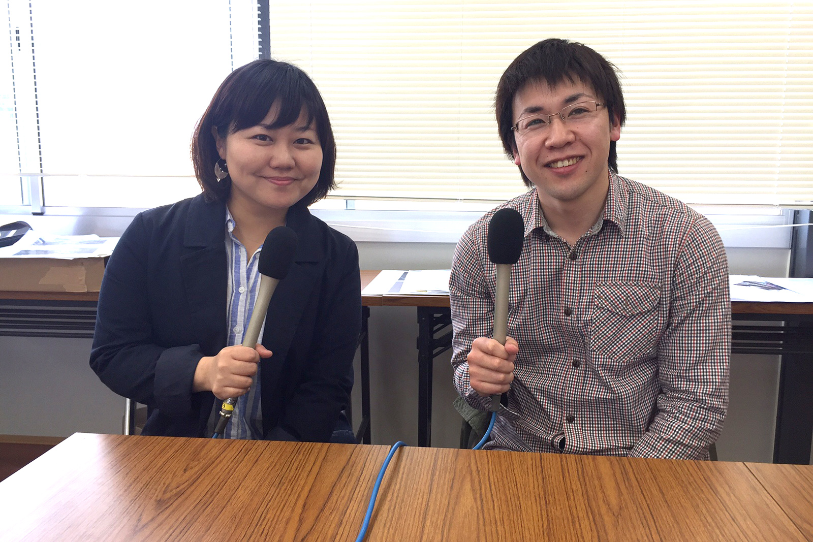 テーブルの後ろにマイクを持って並んで座った笑顔の女性リポーターと伊藤さんの写真