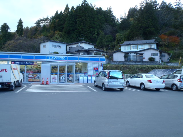 コンビニエンスストアの店舗の隣に太陽光パネルが設置されており、前にある駐車場には複数の車が停まっている写真