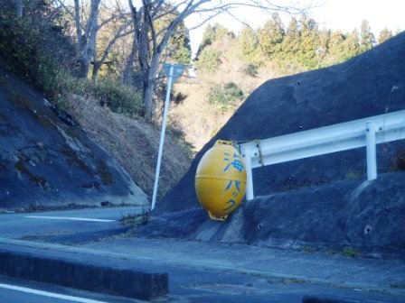 道路沿いにある歩道横にあるガードレールに、黄色い漁業用の浮き玉のようなものに「海パック」と書かれた看板を写した写真