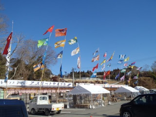 伊里前福幸商店街の店先に立てられた色とりどりのJリーグのフラッグが風になびいている様子を写した写真