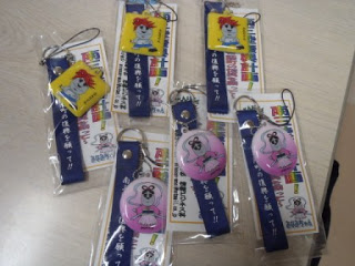 青いストラップで男性モアイ「さんりくん」と女性モアイ「みなみちゃん」の2種類のラッピングされたストラップが3つずつならんでいる写真