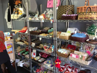 金属製のラックに手作りの雑貨や編み物、かごバッグ、布小物、お菓子などが所狭しと並べられている写真