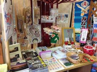 テーブルの上に観光パンフレットや手作りのキーホルダー、ストラップ、小物雑貨が並べられたコーナーの写真