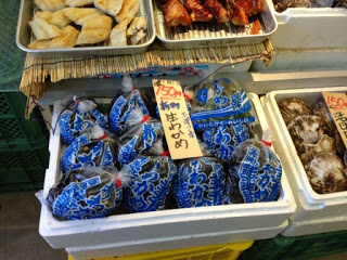店舗の一角にある魚介類売り場で、発泡スチロールの箱の中に袋詰めの生わかめと他の海産物が並べられている魚介類売り場の写真。