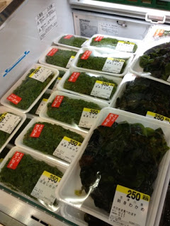 売り場の冷蔵庫の中に、緑色の海藻がパックに入って多数並べられている様子の写真。