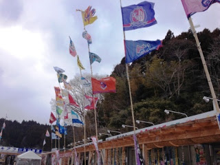 木造の伊里前福幸商店街で、色とりどりのJリーグの旗が何本も立ち並ぶ写真