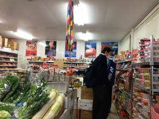 制服姿の男子生徒がお菓子の並んだ陳列棚の前で品物を見ている様子の写真