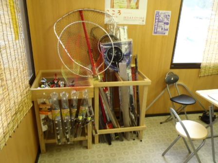 店舗の角に木枠があり、網などの釣り道具が立てて収納されている様子の写真