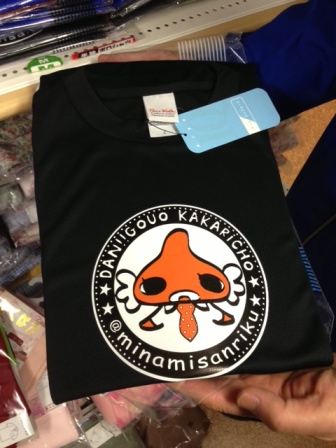 黒いTシャツの中央に、オレンジ色でワイシャツとネクタイを着たダンゴウオ係長のキャラクターが円の中に描かれているデザインTシャツの写真