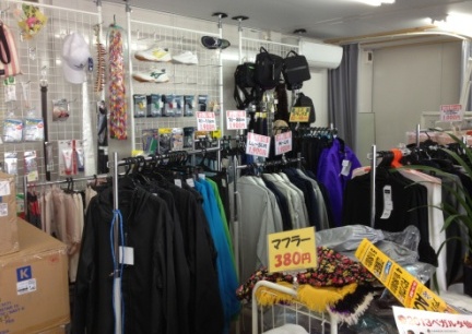 ジャケットやウインドブレーカー、帽子、マフラーなどの衣類や小物がハンガーラックや棚に整然と陳列された店舗内を写した写真