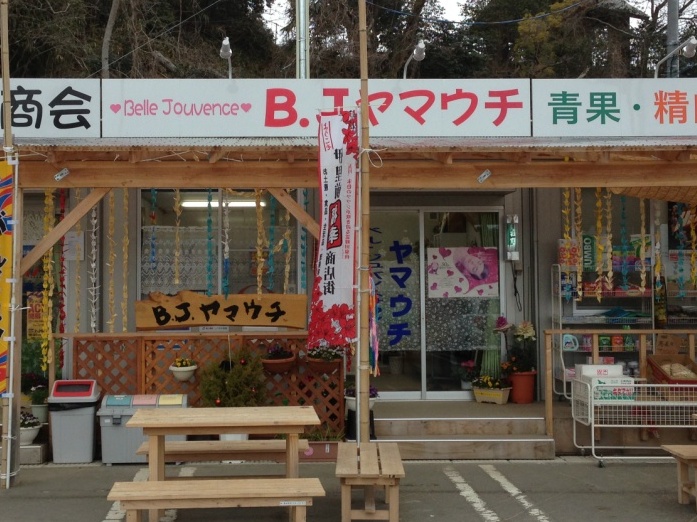 「B.J.ヤマウチ」の看板が掲げられ、店舗前に木製ベンチやのぼりが置かれている、「B.J.ヤマウチ」の外観写真
