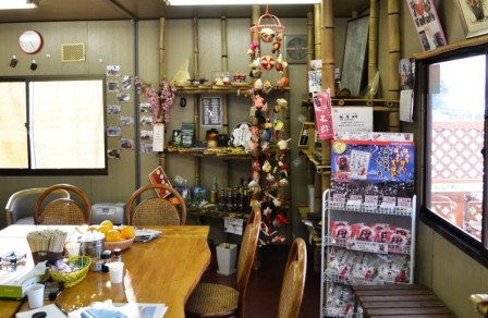 壁際に竹で作られた展示棚にお酒の瓶や装飾品などが飾られた、温かみのある手作り感のある店内の一角を写した写真