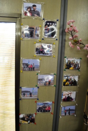 壁に人々の笑顔の写真が何枚もピンで留められている様子を写した写真