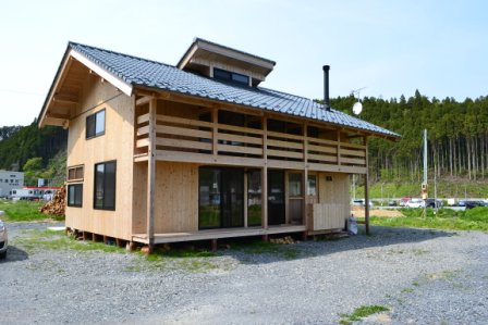 木材をふんだんに使った二階建ての建物が広い空き地に建っており、屋根は瓦葺きで、バルコニーや窓が多く設けられている木造建築の外観の写真