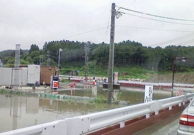 冠水したガソリンスタンドの敷地内で、給油機や電柱が水に浸かっている様子が写っている写真