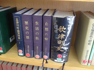 木製の本棚に、5冊の「歌津町史」などの紺色や紫色の厚い歴史関係の本が縦に並んでいる写真