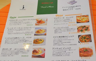 各料理名や値段、写真がカラーで掲載されていて、料理の説明文も丁寧に書かれている、パスタとピザのメニュー表がテーブルに置かれている写真