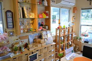 木製の棚に並べられた小物類などが明るい店内の一角にぎっしりと並んでいる雑貨販売スペースの写真