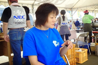青いTシャツを着た紺野禎子さんがテントの中で座って話している様子をアップで撮影した写真