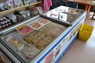 店内の棚に土産物が並んでおり、手前の横長の冷蔵ショーケースの中にロールケーキが陳列されている写真
