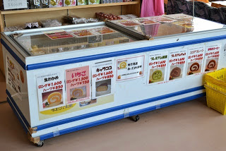 冷蔵ショーケースの側面に7種類のロールケーキの品名と写真、値段が記載されたポップが貼られている写真